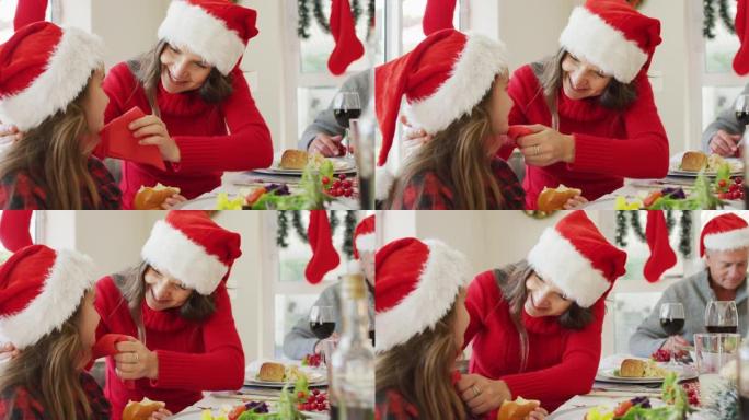 快乐的高加索母亲在圣诞节餐桌上擦女儿的嘴