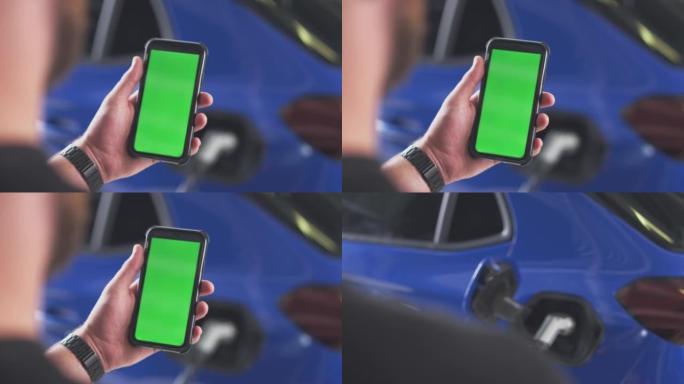 使用手机上的绿屏应用程序在家里的车库里的男人的特写检查电动汽车的电池电量-慢动作拍摄