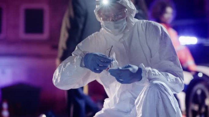 取证小组在行动:专家在工作服检索证据从犯罪现场和放入拉链塑料袋。破碎的血迹斑斑的眼镜可能是凶手的，被
