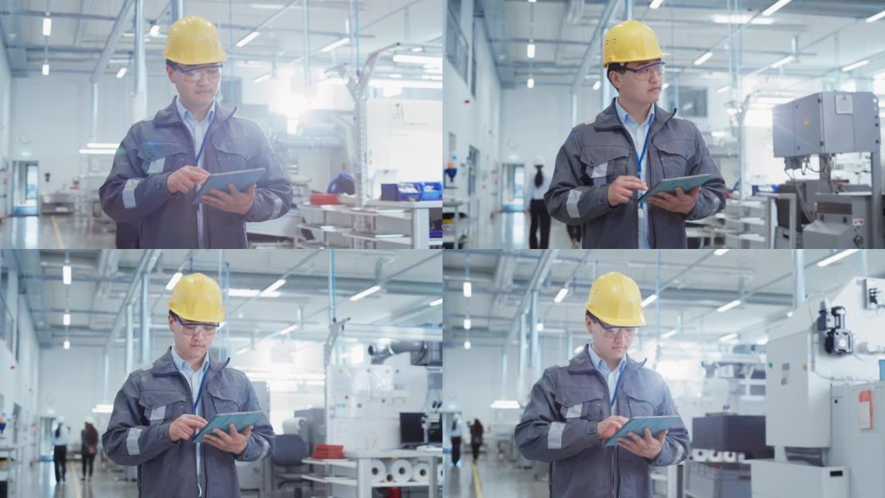 一位年轻的亚洲男子的肖像，在工业设施中担任工程师，穿着工作衣和黄色安全帽。重工业专家步行和使用平板电