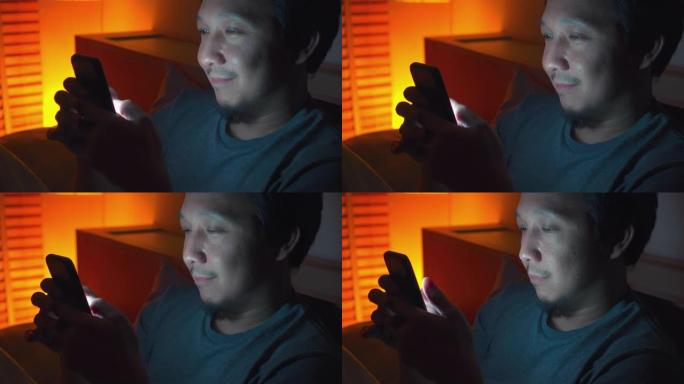 亚洲男子晚上在床上使用智能手机