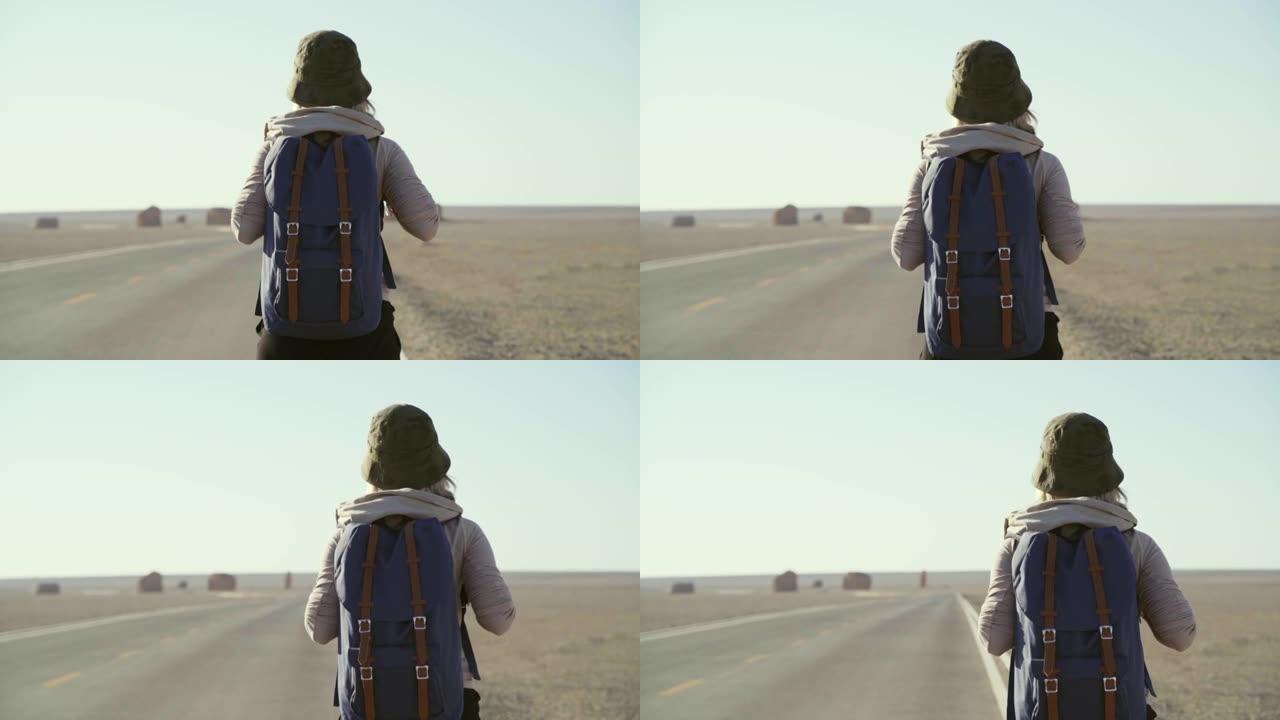 亚洲女性徒步旅行者在沙漠中的高速公路上行走