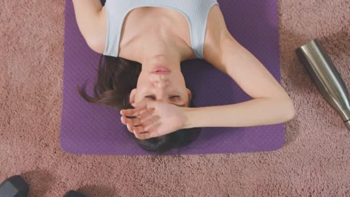 锻炼后，女人在家里的运动垫上休息的头顶镜头