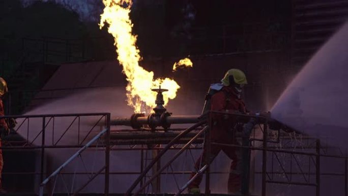 4k UHD消防员使用水雾式灭火器与石油钻机和天然气站的石油管道泄漏和爆炸引起的火焰进行战斗。消防员