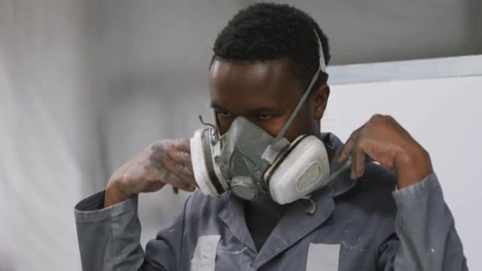 非裔美国男性汽车修理工在乡镇车间工作并戴上口罩