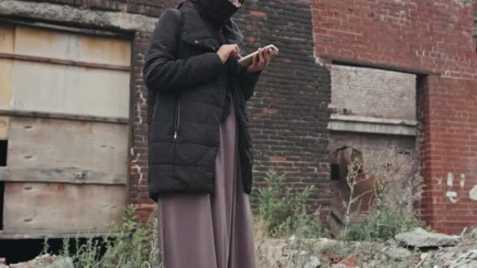 难民妇女在废弃地区使用智能手机