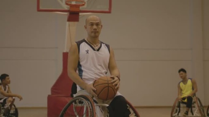 亚洲男子轮椅篮球在健身房看着相机。