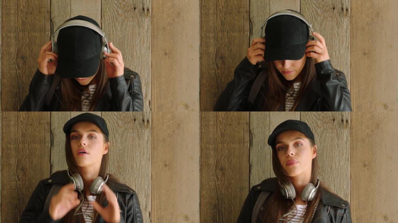 一位很酷的大学生，在木墙上戴着耳机听音乐。一个很酷的年轻女子通过听耳机欣赏音乐
