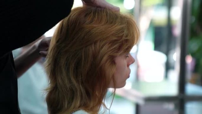 金发碧眼的顾客使用理发服务。正在与理发师一起使用美发沙龙中的服务。