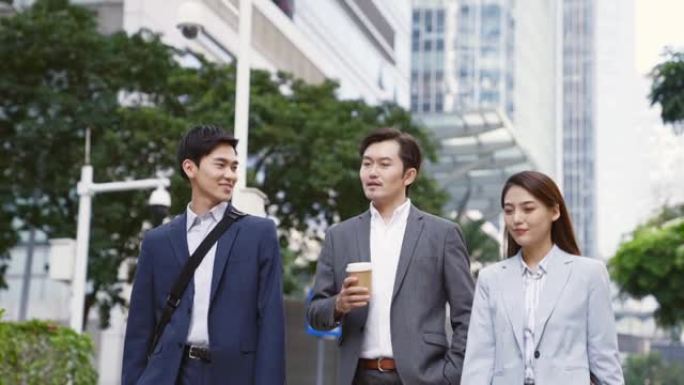 三名亚洲商务通勤者在现代城市的街道上行走