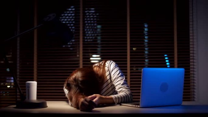 精疲力竭的女人坐在家里的办公桌前在笔记本电脑上工作