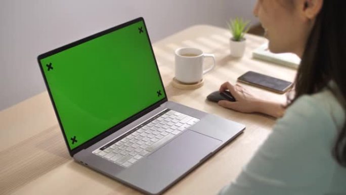 女人在家中使用带有绿屏的笔记本电脑