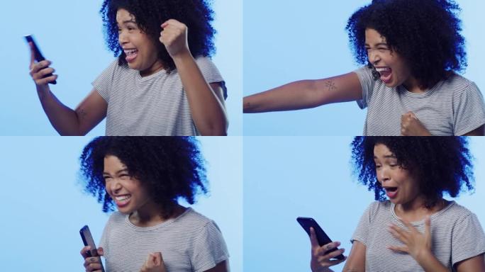 4k视频片段，一个美丽的年轻女子在蓝色背景下使用手机时欢呼