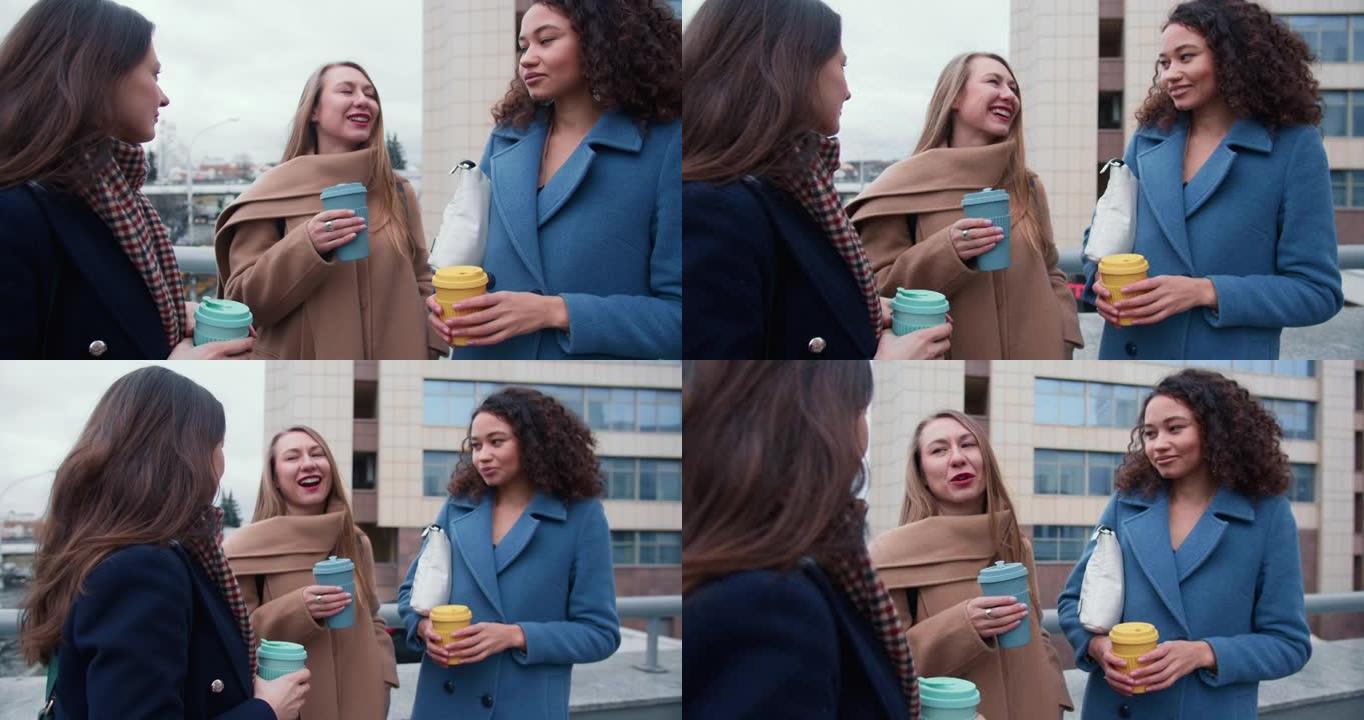 放大年轻快乐美丽多样的女性朋友聊天，在市中心外面的生态杯子里拿着咖啡。