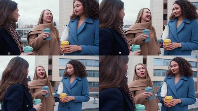 放大年轻快乐美丽多样的女性朋友聊天，在市中心外面的生态杯子里拿着咖啡。