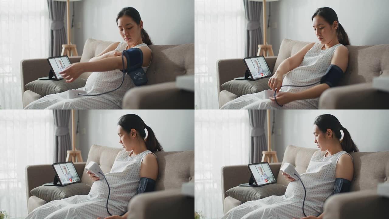年轻的孕妇在数字平板电脑上与医生交谈并在家中检查血压