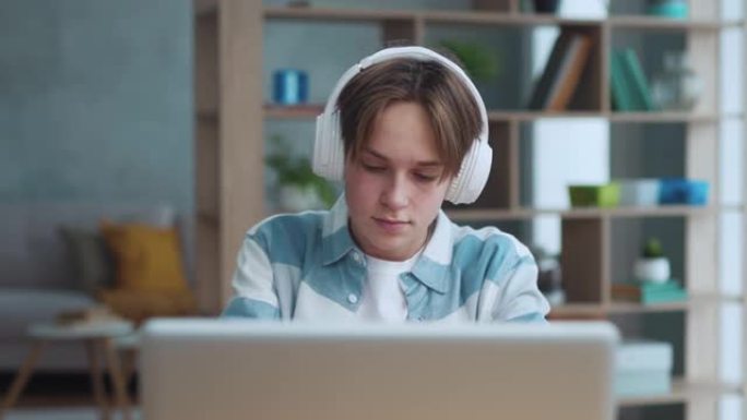 聪明的少年盖伊戴上耳机在家近距离听音乐。迷人的少年男孩放松在音频设备上的歌曲声音。英俊的年轻学生在最