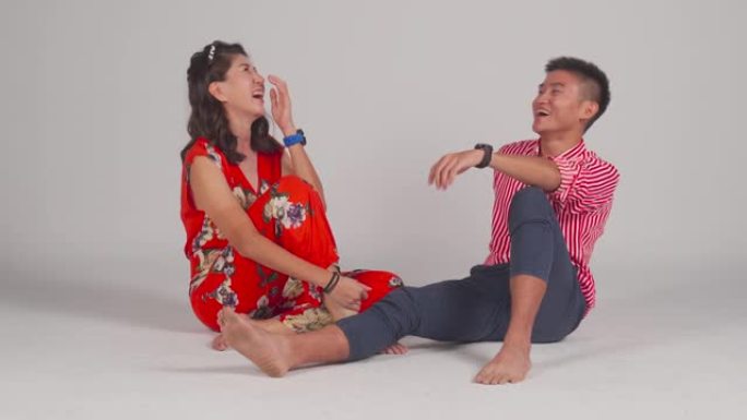 时尚的亚洲中国朋友坐在地上笑着夏天穿工作室拍摄与灰色背景剪裁