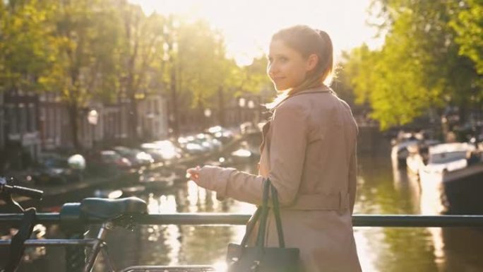 在春天美丽的晴天，女人在桥上俯瞰阿姆斯特丹运河，闪闪发光的水