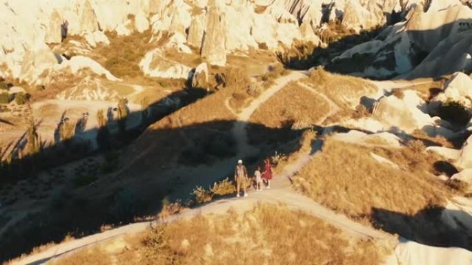 电影空中全景，带着孩子在日出山顶的快乐旅游家庭欣赏卡帕多西亚之旅的景色。