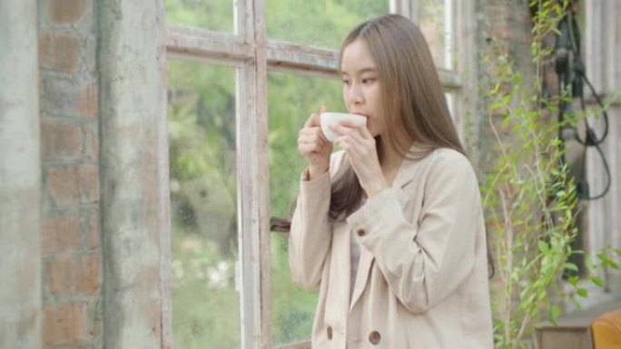 女人在雨天喝咖啡，享受窗外的味道。