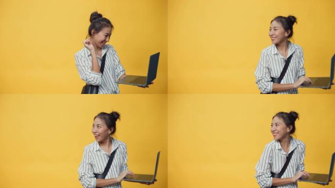 快乐美丽亚洲青年休闲女孩打字笔记本电脑站在孤立的黄色空白空间背景微笑给标志展示成功购买在线广告。