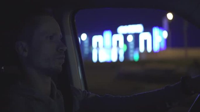 年轻有魅力的男人正在夜市道路上驾驶汽车