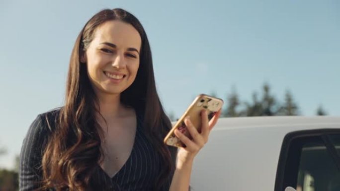 年轻女子在给电动车充电时使用手机和拿着咖啡杯的肖像