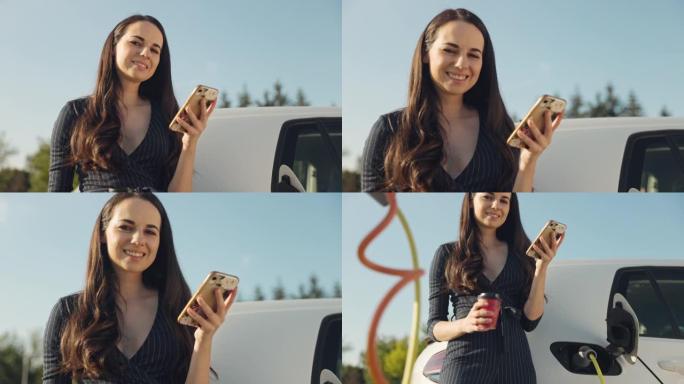 年轻女子在给电动车充电时使用手机和拿着咖啡杯的肖像