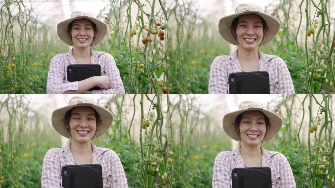 亚洲农民站在温室里，她拿着数字平板电脑，自信地看着相机。她有了一项新业务，并且很享受。