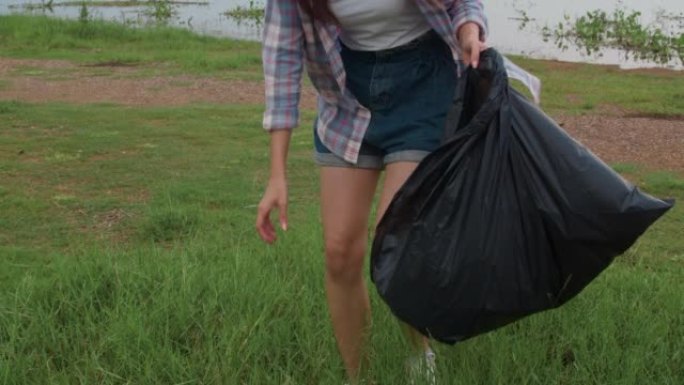 快乐的年轻亚洲活动家在海滩上收集塑料垃圾。