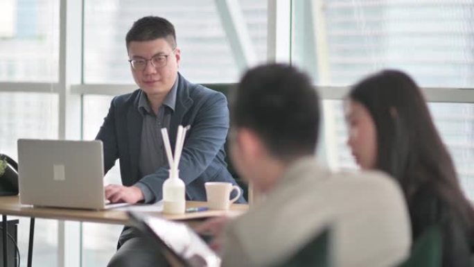 亚洲华人经理与他的2位同事在办公室进行业务绩效会议讨论