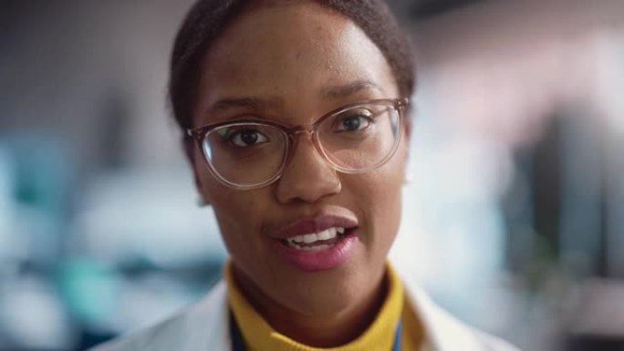 穿着实验室外套和眼镜微笑的年轻黑人女性专家的肖像特写。专业而成功的女性担任工程师，开发高科技项目