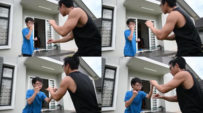 一名亚洲华裔父亲运动员在晚上的武术中训练他12岁的儿子在房子的前院