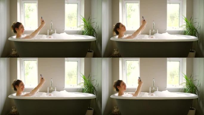 4k视频片段，一名年轻女子在泡泡浴中用手机自拍