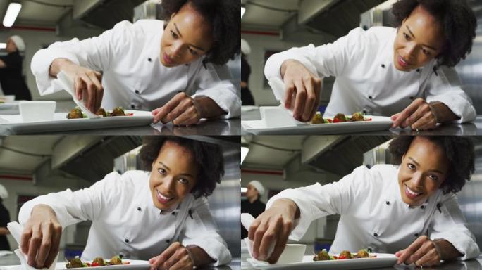 非裔美国女厨师装饰菜肴的肖像看着相机和模仿