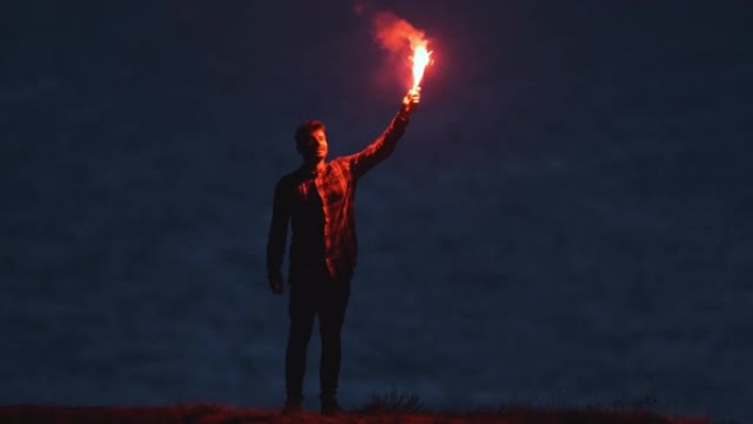 那个英俊的男人站在海边，拿着一根火棍。慢动作