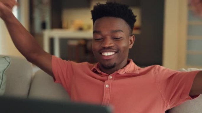 在线学习愉快，沙发上有笔记本电脑的男人，看着屏幕很满意。黑人男性通过电脑在互联网上接受教育。年轻的学