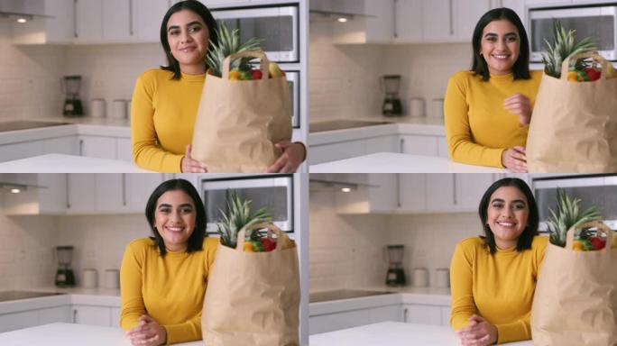 4k视频片段，一名年轻女子从家里厨房的纸袋中打开新鲜农产品的包装