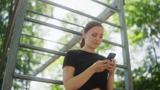 女人在户外健身房检查她的智能手机