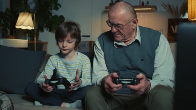 可爱的十几岁男孩孙子教快乐的60多岁祖父在家沙发上玩操纵杆的游戏机游戏。