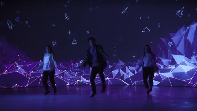由三名专业舞者组成的多元化小组，在工作室环境中的虚拟制作期间，在带有VFX动画的大Led墙屏幕前表演