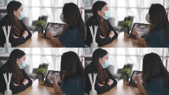 亚洲华裔女牙医在她的办公室向一名女患者解释医学x射线图像