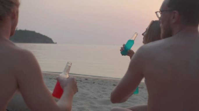 日落日，一群年轻的多民族的五个朋友坐在美丽的大海前玩得开心。假期-iStock概念。