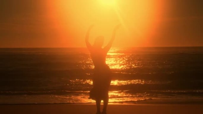 女人的SLO MO剪影在日落时在海滩上表演慢舞