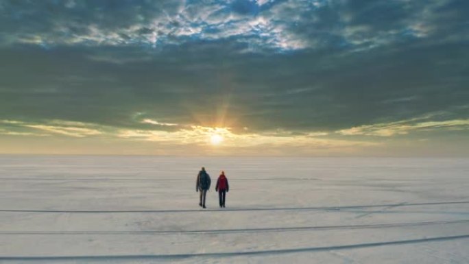 背着背包的两个人在冰冷的湖面中穿行