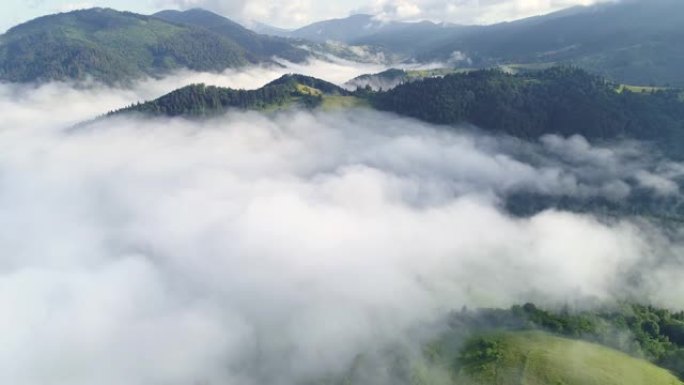 在雾蒙蒙的绿色山丘上飞过云层。清晨被森林覆盖的壮丽山脉。生态旅游和乡村娱乐。空中射击，4K