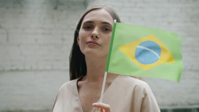 举着巴西国旗站在户外的迷人女人的慢动作肖像