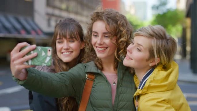 一群度假的朋友在城市外用手机自拍。时髦时尚的女性在暑假期间一起拍照，在社交媒体上发帖