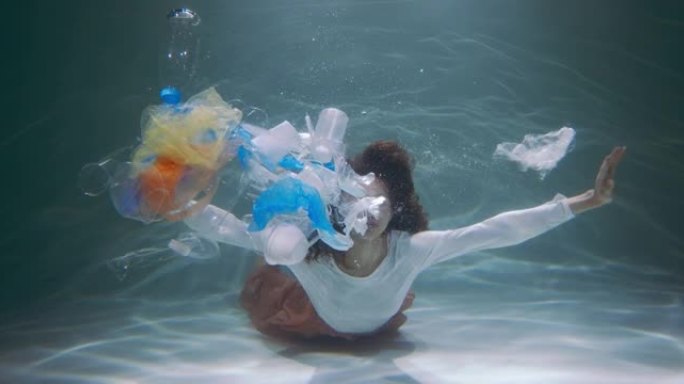 塑料垃圾足迹。年轻女子扔掉垃圾袋，各种垃圾漂浮在水下慢动作。